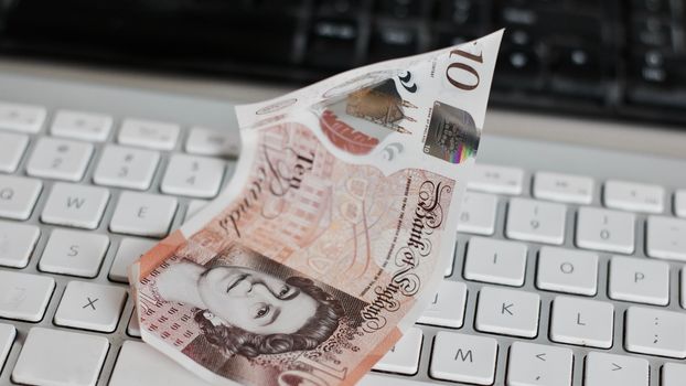 British money on the white keyboard in the office. Money concept.