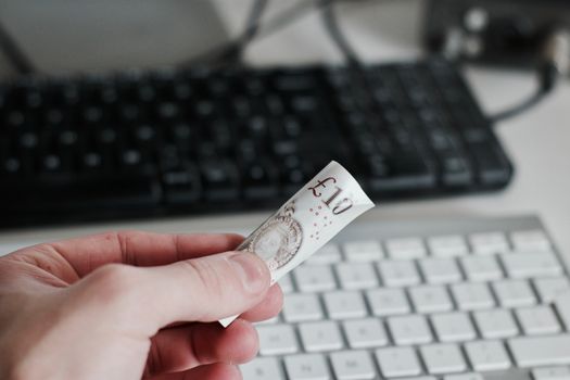 British paper money in hand near white computer keyboard. Money concept.