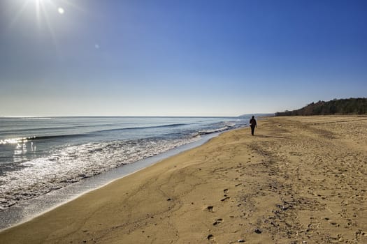 woman in summer walking in the sand by the sea beach