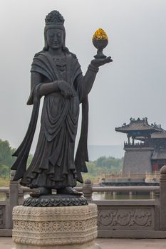 A large stone carved statue of a Buddhist Diety holding a golden object.