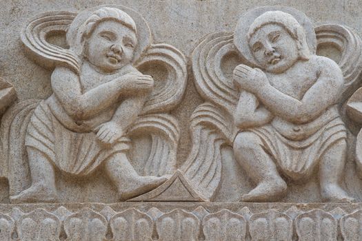 Mural of children dancing carved in stone wall.