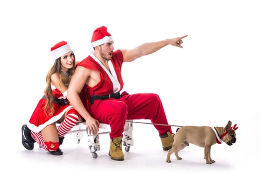 Handsome young man and pretty young woman in Santa Claus hat and costume, with pug dog, standing holding colorful festive Christmas gifts to celebrate the season, on white background