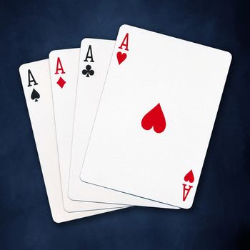 A winning poker hand of four aces playing cards suits on blue background