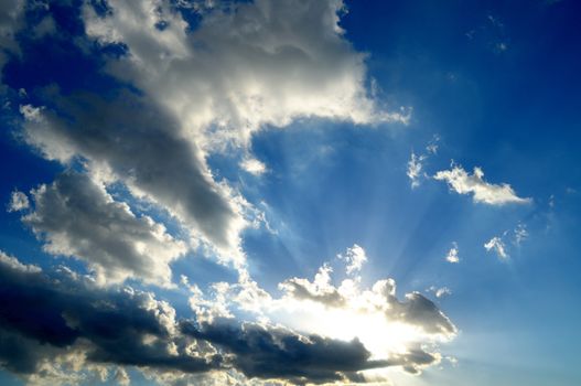 sunrays across clouds in a twilight blue sky