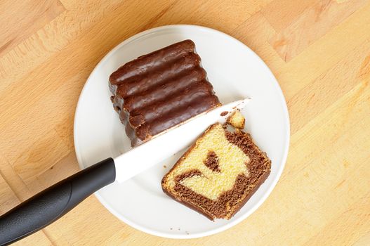 Top view of delicious chocolate marbled cake cutting with a white ceramic knife