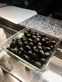 Fresh and tasty black olives on a glass plate. Healthy food concept.