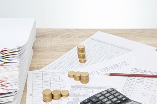 Pencil and step pile of gold coins on finance account have blur overload report with calculator on wooden table with white background and copy space. Business and finance concept rich and successful.