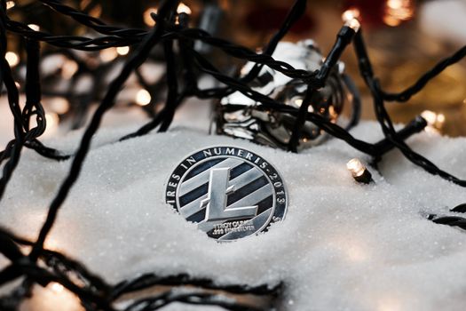 Digital currency physical metal silver litecoin coin. Christmas snow concept.