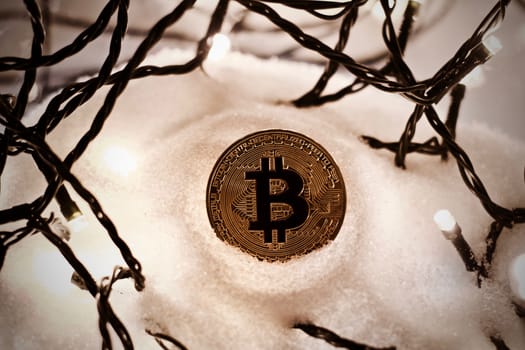 Digital currency physical metal bitcoin coin. Crypto currency christmas snow composition.