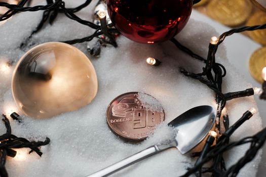 Digitl currency physical metal brass dogecoin coin. Christmas snow concept.