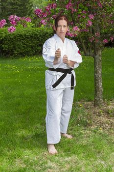 forty something martial artist woman in fighting stance, under a cherry tree