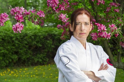 forty something martial artist woman with serious glare, under a cherry tree