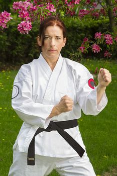forty something martial artist woman in fighting stance, under a cherry tree