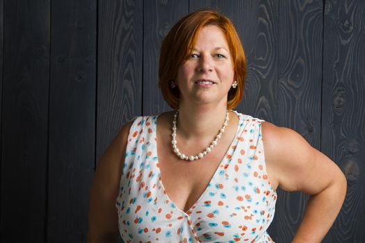 forty something woman wearing a sundress in front of a blue stain background