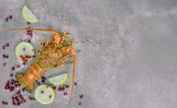 Top view of steamed lobster with lemon and pomegranate  on cement background