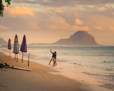 Man and woman on sea shore taking selfie with mobile phone at sunset.Horizontal shot of loving young couple taking self portrait at the amazing beach .