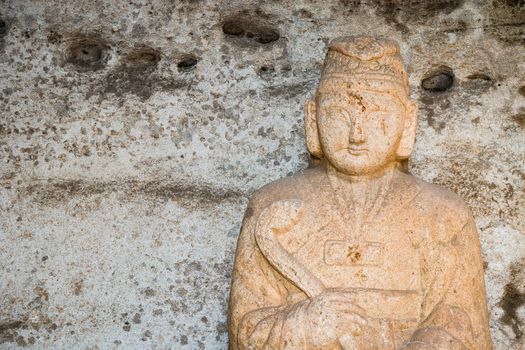 A sculpture of  Buddha carved into a beige colored stone