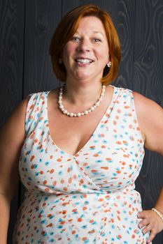 woman in her forties, in front of a blue stain wood background, with a great smile