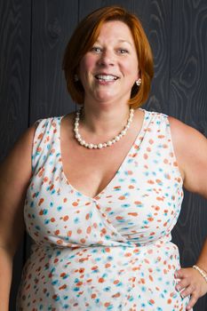 woman in her forties, in front of a blue stain wood background, with a great smile