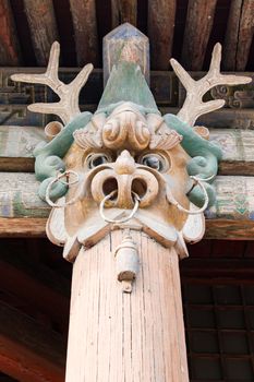 A dragon head carved into the top of a wooden support pillar.