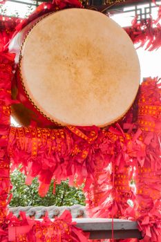 Close up of a prosperity drum with symbolic wish ribbons tied around the stand.