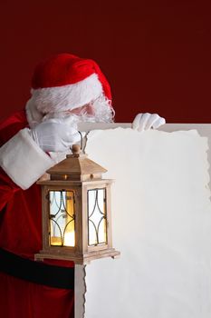 Santa Claus with lantern holding vintage paper billboard with copy space for text