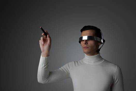 Man using futuristic VR goggles headset with microphone and touching virtual screen with digital pen