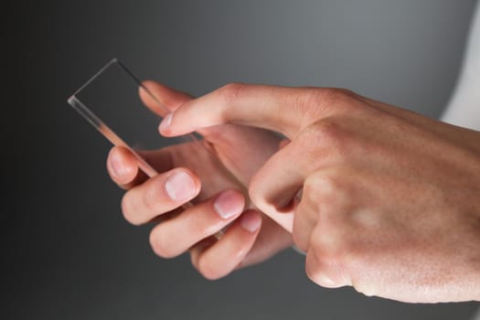 Male hands holding blank futuristic transparent mobile, smart phone with copy space