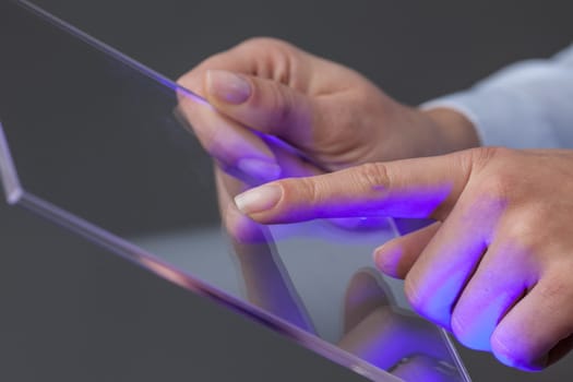 Female hands holding blank futuristic transparent digital tablet pc computer with copy space