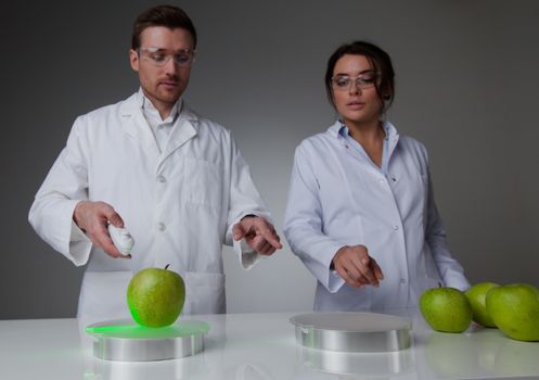 Two scientists in laboratory doing futuristic research experiments with apples, teleportation or cloning concept