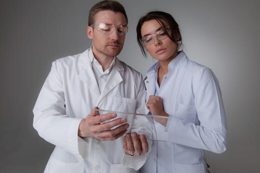 Two scientists or doctors holding blank futuristic transparent digital tablet pc computer with copy space