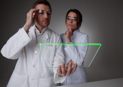 Two scientists or doctors holding blank futuristic transparent digital tablet pc computer with copy space