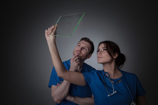Healthcare, medicine and technology concept - two doctors holding futuristic transparent tablet pc