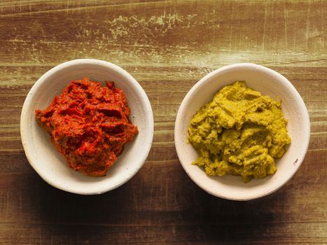 close up of bowls of rustic red and yellow indian curry paste