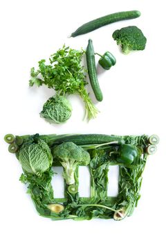 Grocery basket icon with green fruits and vegetables falling in over a white background