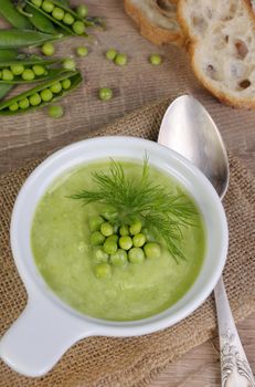 A plate of soup puree of green peas with dill on a table
