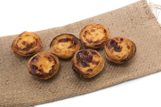 Famous Portuguese egg pastry tart called 'Pastel de Belem' on hessian fabric.