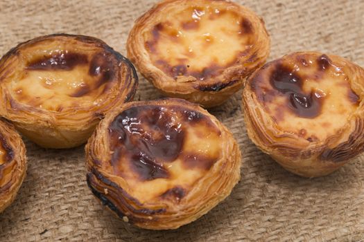 Famous Portuguese egg pastry tart called 'Pastel de Belem' on hessian fabric.