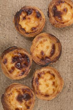 Famous Portuguese egg pastry tart called 'Pastel de Belem' on hessian fabric.