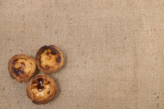 Famous Portuguese egg pastry tart called 'Pastel de Belem' on hessian fabric.
