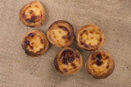 Famous Portuguese egg pastry tart called 'Pastel de Belem' on hessian fabric.