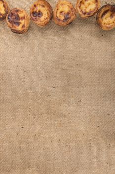 Famous Portuguese egg pastry tart called 'Pastel de Belem' on hessian fabric.