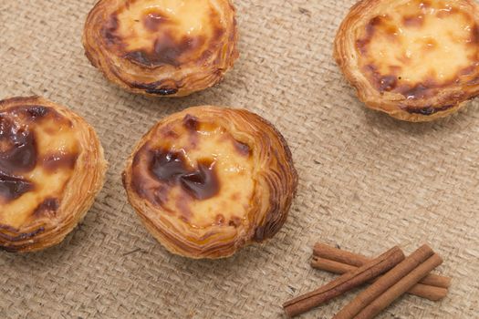 Famous Portuguese egg pastry tart called 'Pastel de Belem' on hessian fabric.