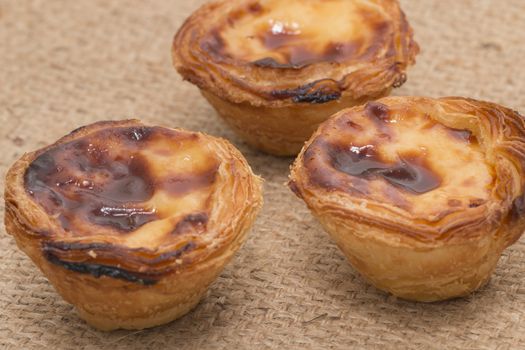 Famous Portuguese egg pastry tart called 'Pastel de Belem' on hessian fabric.