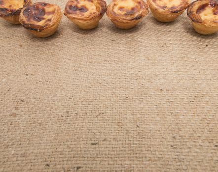 Famous Portuguese egg pastry tart called 'Pastel de Belem' on hessian fabric.