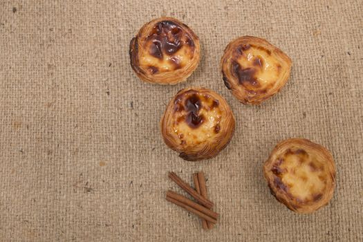 Famous Portuguese egg pastry tart called 'Pastel de Belem' on hessian fabric.