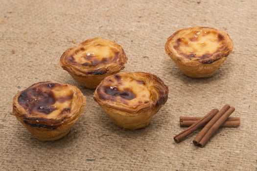 Famous Portuguese egg pastry tart called 'Pastel de Belem' on hessian fabric.