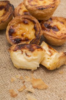 Famous Portuguese egg pastry tart called 'Pastel de Belem' on hessian fabric.