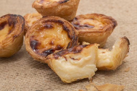 Famous Portuguese egg pastry tart called 'Pastel de Belem' on hessian fabric.
