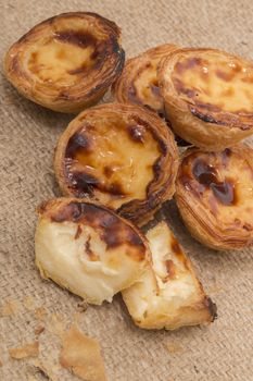 Famous Portuguese egg pastry tart called 'Pastel de Belem' on hessian fabric.